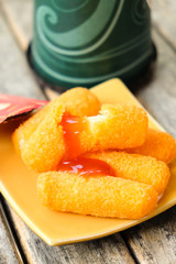 Fried cheese sticks in pan with tomato sauce