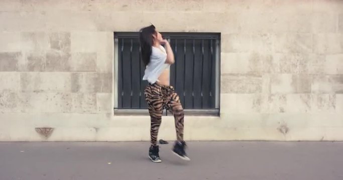 Contemporary funky asian woman street dancer dancing freestyle in the city