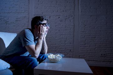  television addict man on sofa watching TV and eating popcorn in funny nerd geek glasses