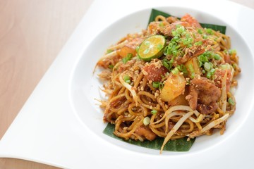 Asian style spicy fried noodles, ready to serve on dining table.