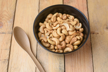 Raw cashews close-up in bowl on wood background