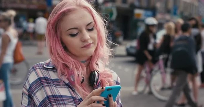 Slow Motion Portrait of caucasian girl with pink hair using smart phone