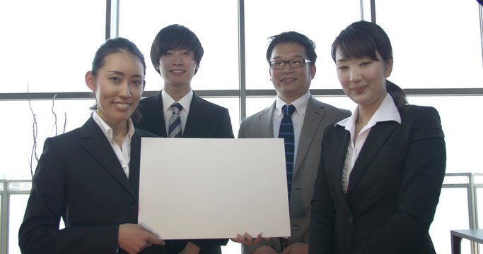 Japanese company team points to white sign