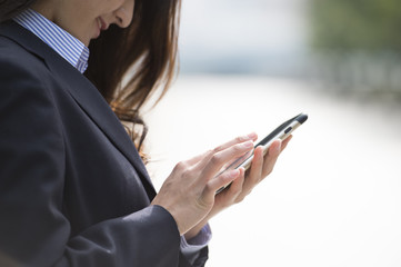Woman wearing a business suit is looking at the information in the smartphone