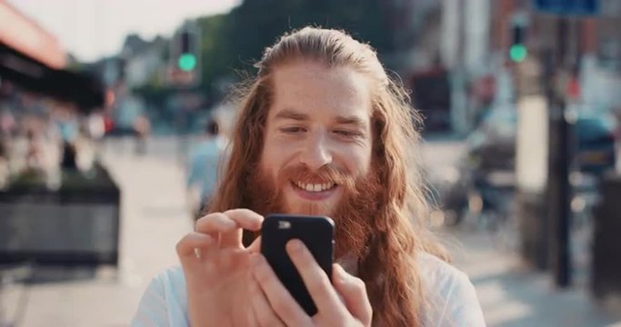 Slow Motion Portrait of happy hipster man with beard using smart phone