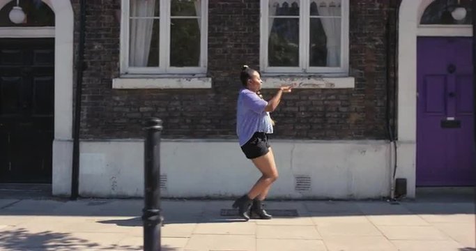 Contemporary funky African American woman street dancer dancing freestyle in the city
