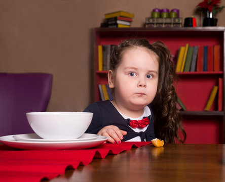Funny little girl sitting at the table