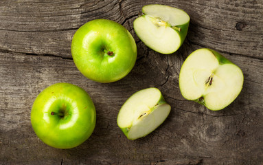 ripe green apples and apple slices on wooden gray background