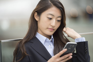 Asian woman wearing a suit has a smart phone