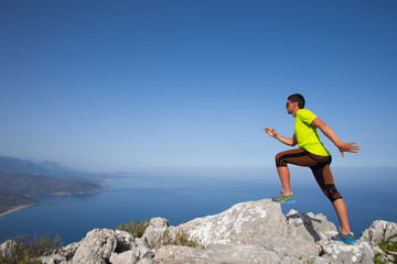 Man practicing trail running with a coastal landscape in the background.