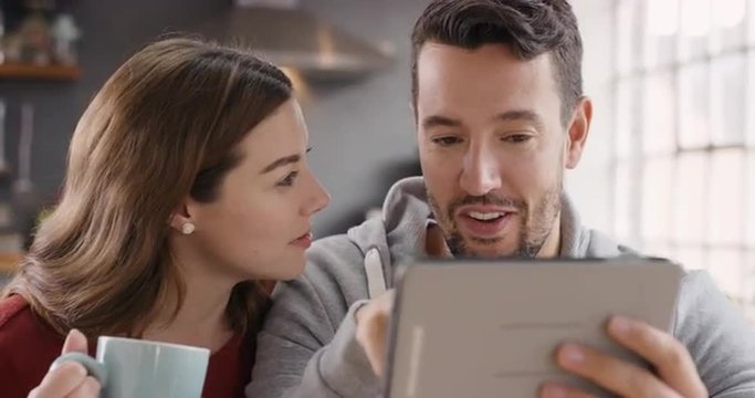 Happy couple using digital tablet at home spending time together