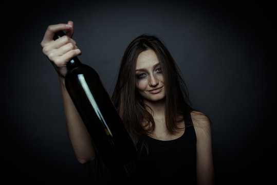 The social problem. Young unhappy woman uses alcohol from a bott