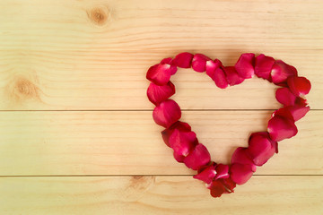 Heart shape made out of rose petals on wood background, Valentin