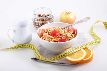 muesli with Apple, orange and measuring tape on white background
