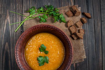 Bowl of pumpkin soup with bread crouton on wood table