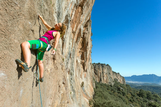 Youth female Rock Climber hanging on vertical Wall