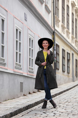 Beautiful Asian woman with a coat and a black hat walking on the street of a European city