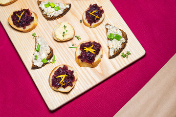 Fototapeta na wymiar Wooden tray of appetizers on pallet coffee table at banquet with beetroot, citron, green herbs and hummus.