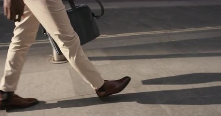 Close crop of businessman feet walking in city