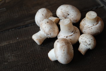 Heap of white button mushrooms on dark brown wooden background - close-up