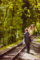 Happy newlywed romantic couple walking on rails in the park