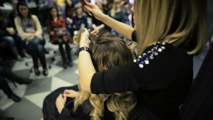 master class in the art of hairdressing, model, and a lot of students of hairdressers in the background.