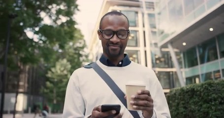 African American businessman walking through city using smart phone - Powered by Adobe