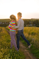 Fototapeta premium Boy and girl holding hands and walking along the road