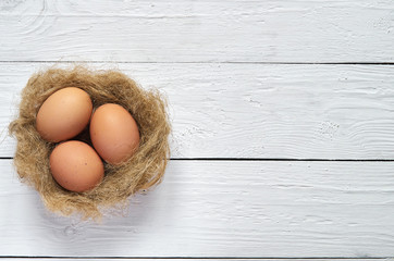 Nest with eggs on white wooden planks background. Easter greeting postcard template. Space for copy, text, lettering.