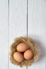 Nest with eggs on white wooden planks background. Easter greeting postcard template. Space for copy, text, lettering.
