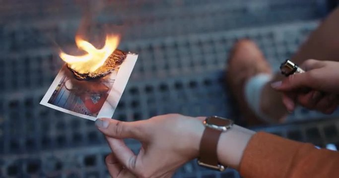 Beautiful sad woman burning photograph of her ex-boyfriend lover
