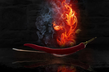 Red Chili laid on a fork burning very hot and reflecting in the water