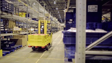 Man driving forklift and loading cargo on rack in warehouse