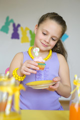 Adorable little girl with cupcakes in Easter scene