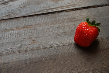 Red ripe strawberry on old wooden table, close-up