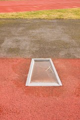 Detail of take-off board on track and field for pole vault high jump. Winter season