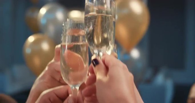 Friends holding up champagne flutes together in a toast at party