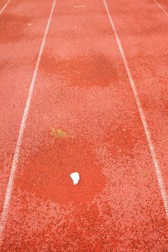 Snow on ground.  White lines and texture of running racetrack, red racetrack,  in outdoor stadium
