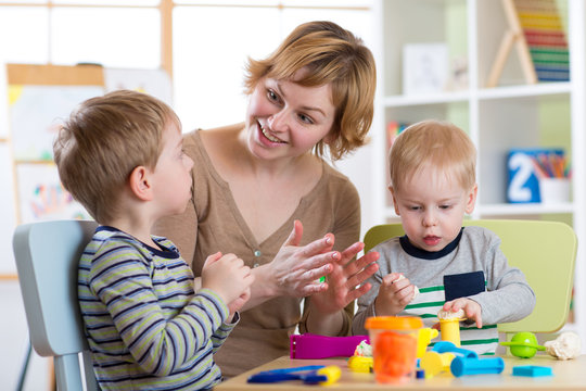 Woman teaches children modeling plasticine in day care center