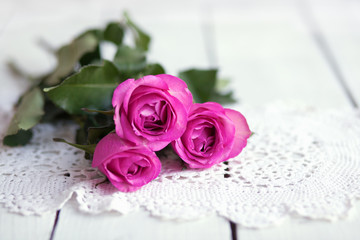 Pink rose on wood table with vintage napkin