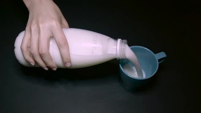 Woman Pouring Milk Into a Blue Cup