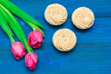 cupcakes with cream and tulips on blue boards