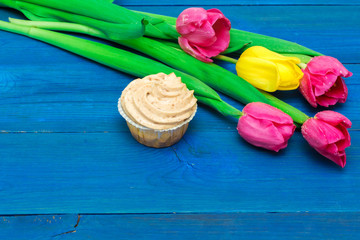 cupcake with cream and tulips on blue boards