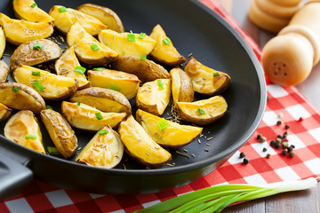 Crispy fried potato wedges on a pan, vegetarian food, close-up