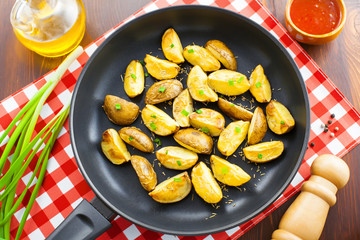 Fresh crispy potato wedges on a pan, vegetarian healthy food, top view