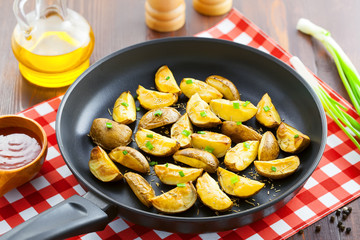 Crispy fried potato wedges on a pan, vegetarian food