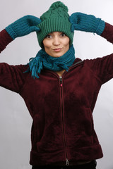 giovane  vestita con cuffia sciarpa e guanti di lana si mette le mani in testa.