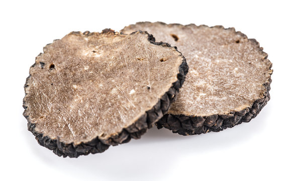 Slices of black summer truffle on a white background.