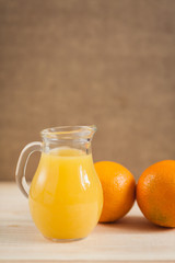 Fototapeta na wymiar Orange juice in clear jar on a wooden background