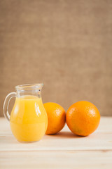 Obraz na płótnie Canvas Orange juice in clear jar on a wooden background